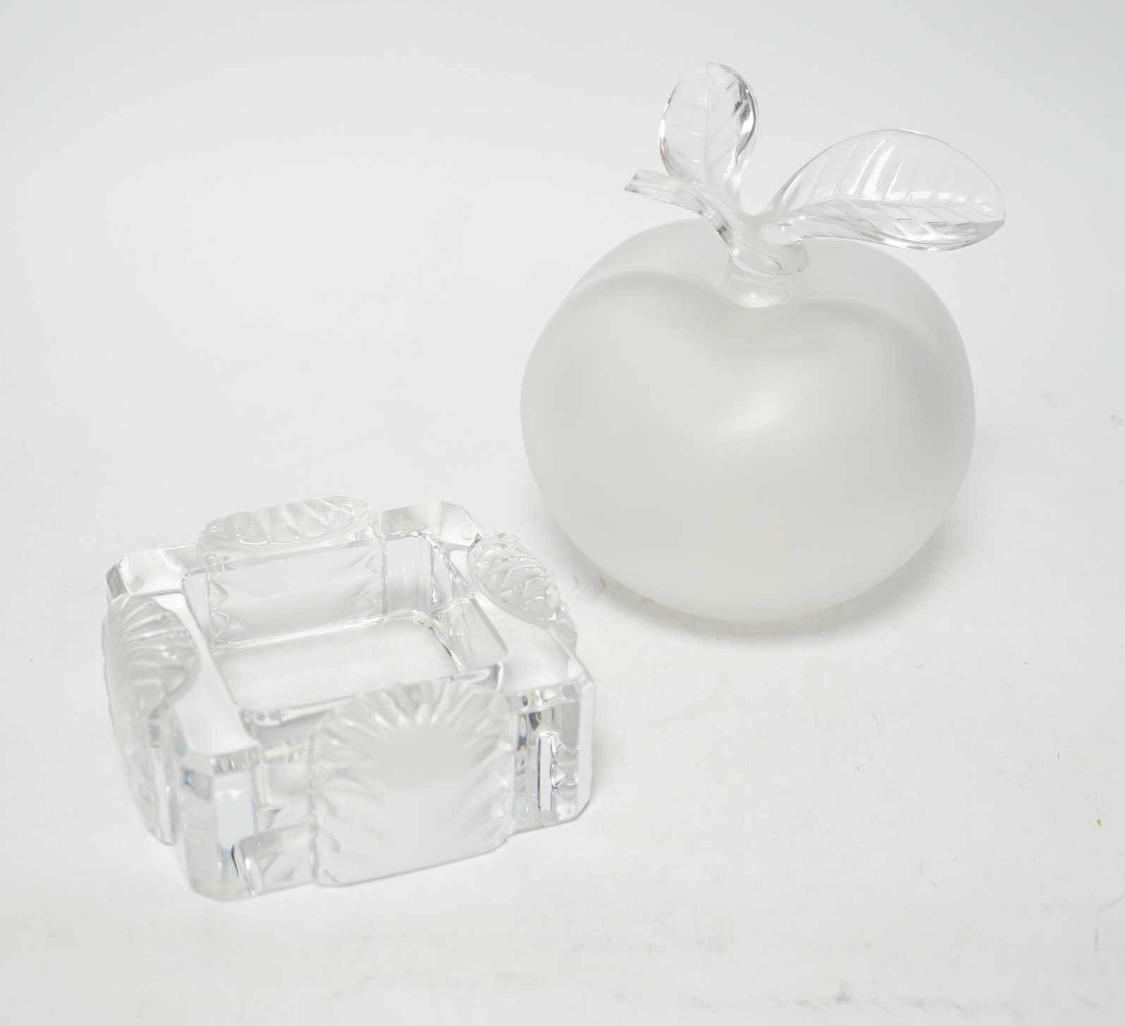 A Lalique apple shaped perfume bottle and leaf stopper together with a square ashtray, both with signed engraving to base, perfume bottle 14cm high